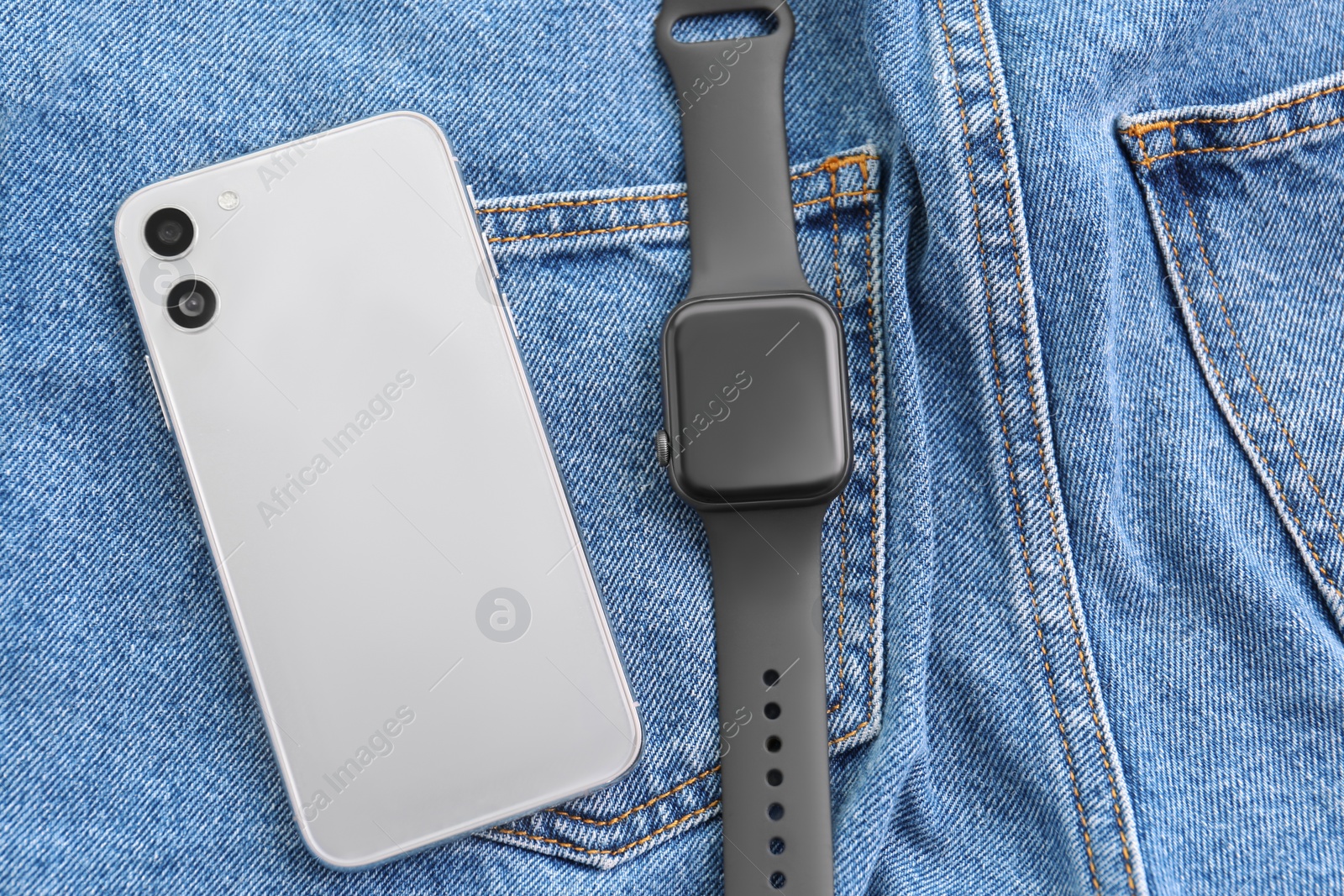Stylish smart watch and phone on jeans, flat lay Photo of Stylish smart watch and phone on jeans, flat lay