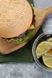 Photo of Delicious cheeseburger and drink on grey textured table, top view