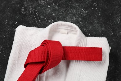 Photo of Red karate belt and white kimono on gray textured background, top view