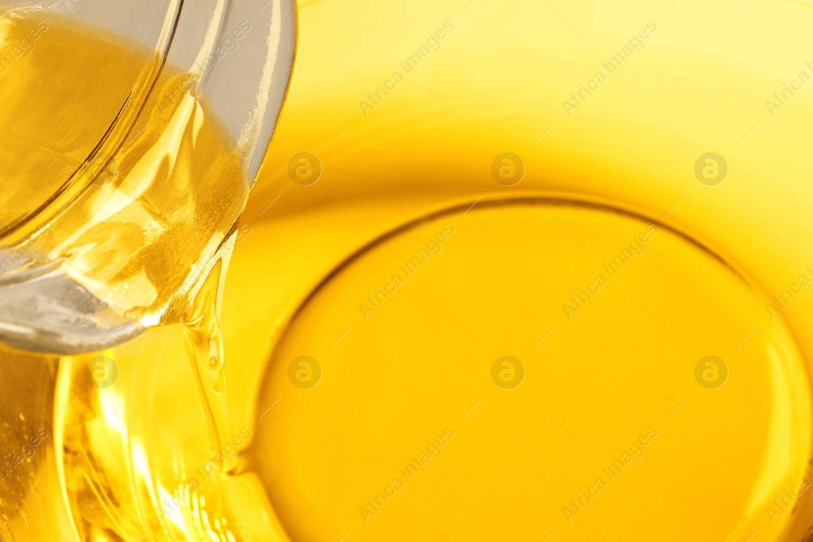Photo of Pouring cooking oil from jug into bowl, closeup