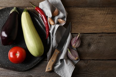 Photo of Cooking ratatouille. Vegetables and knife on wooden table, flat lay. Space for text