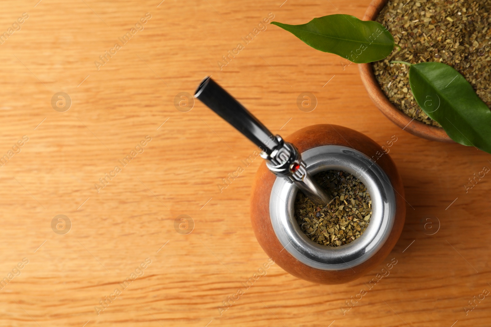 Photo of Calabash with mate tea and bombilla on wooden table, flat lay. Space for text