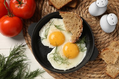Delicious fried eggs served with bread on white wooden table, flat lay