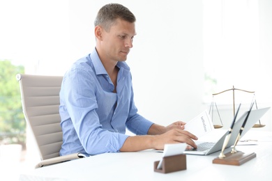 Photo of Male notary working with laptop at table in office