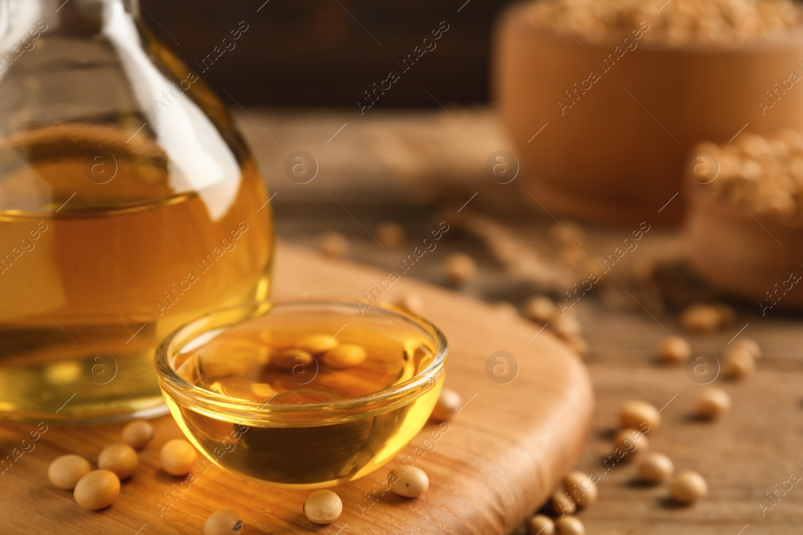 Photo of Bowl of oil and soybeans on wooden board, closeup. Space for text