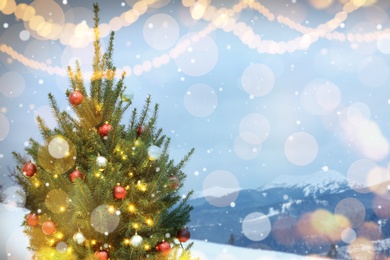 Image of Beautiful decorated Christmas tree outdoors, space for text. Bokeh effect