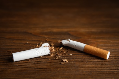 Photo of Broken cigarette on wooden table, closeup. Quitting smoking concept