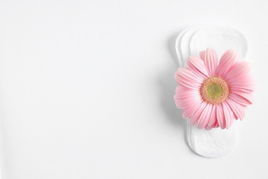 Menstrual pads and gerbera flower on white background, top view. Gynecological care