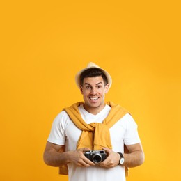 Photo of Excited male tourist with camera on yellow background