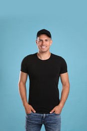 Photo of Happy man in black cap and tshirt on light blue background. Mockup for design