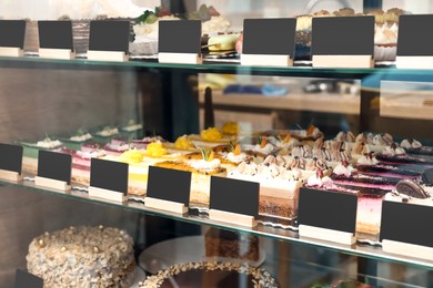 Photo of Showcase with different tasty desserts in bakery shop, closeup