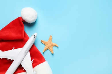 Photo of Santa hat with toy airplane, starfish and space for text on light blue background, flat lay. Christmas vacation