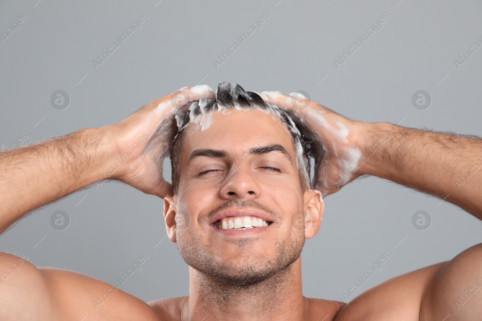 Photo of Handsome man washing hair on grey background