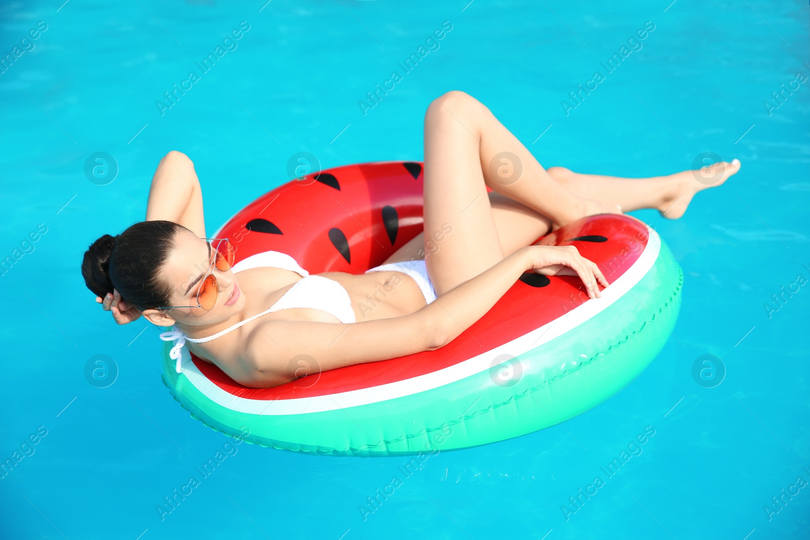 Photo of Beautiful young woman wearing bikini on inflatable ring in swimming pool