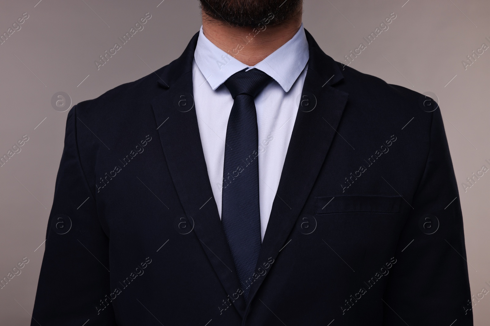 Photo of Businessman in suit and necktie on grey background, closeup