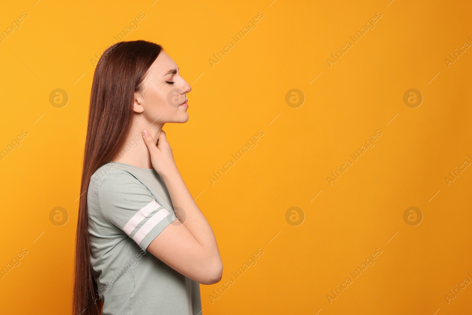 Photo of Young woman with sore throat on orange background