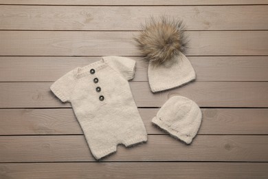 Set of cute baby knitwear for photoshoot on wooden background, flat lay