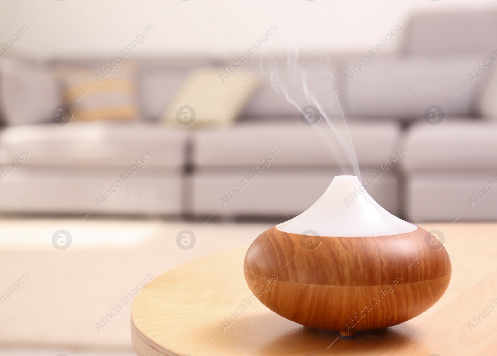 Photo of Modern essential oil diffuser on table in room. Space for text