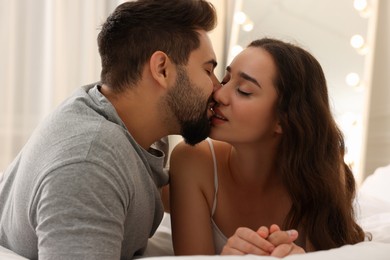 Photo of Passionate young couple kissing on bed indoors