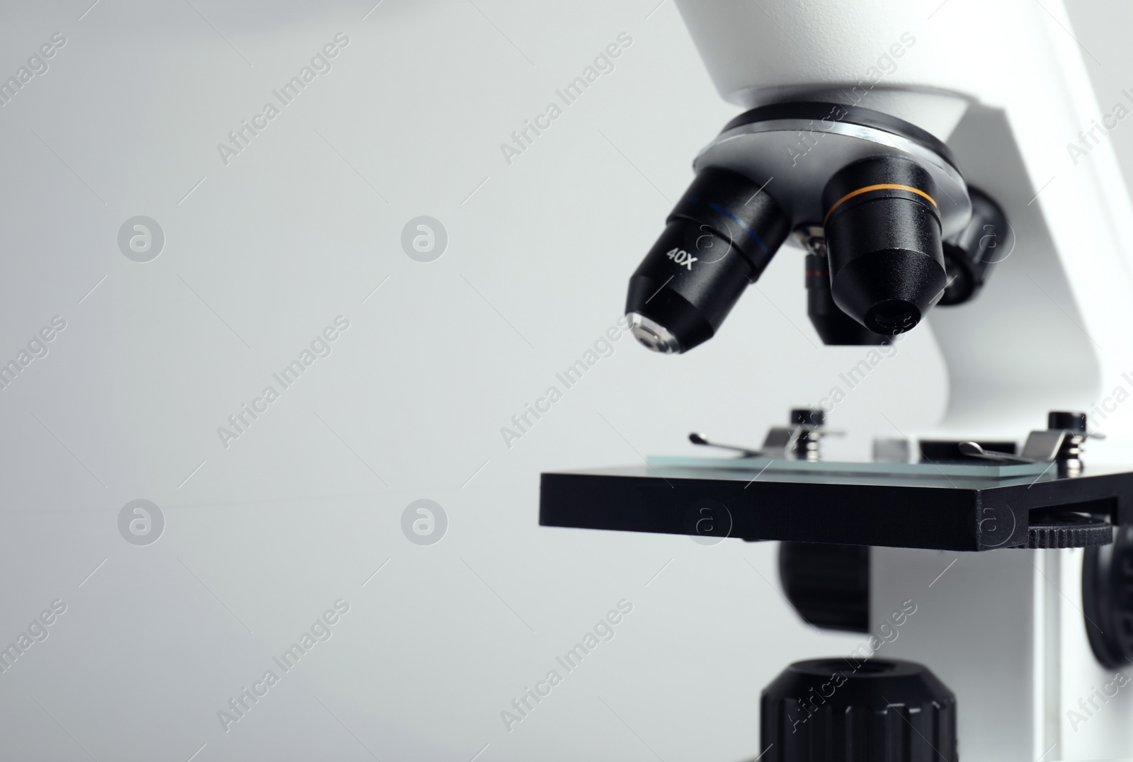 Photo of Closeup view of modern microscope on grey background, space for text. Medical equipment