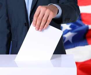 Image of Election in USA. Man putting his vote into ballot box and American flag on background, closeup