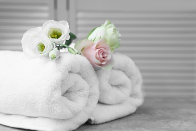 Photo of Rolled towels and flowers on grey table indoors