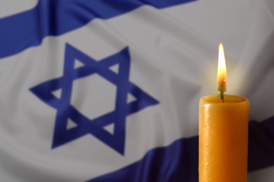 Image of Burning candle against flag of Israel, closeup