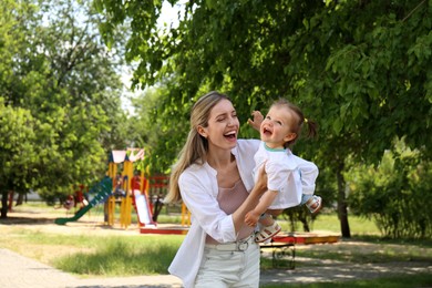 Happy mother with her daughter having fun in park