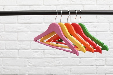 Clothes hangers on metal rail against brick wall background