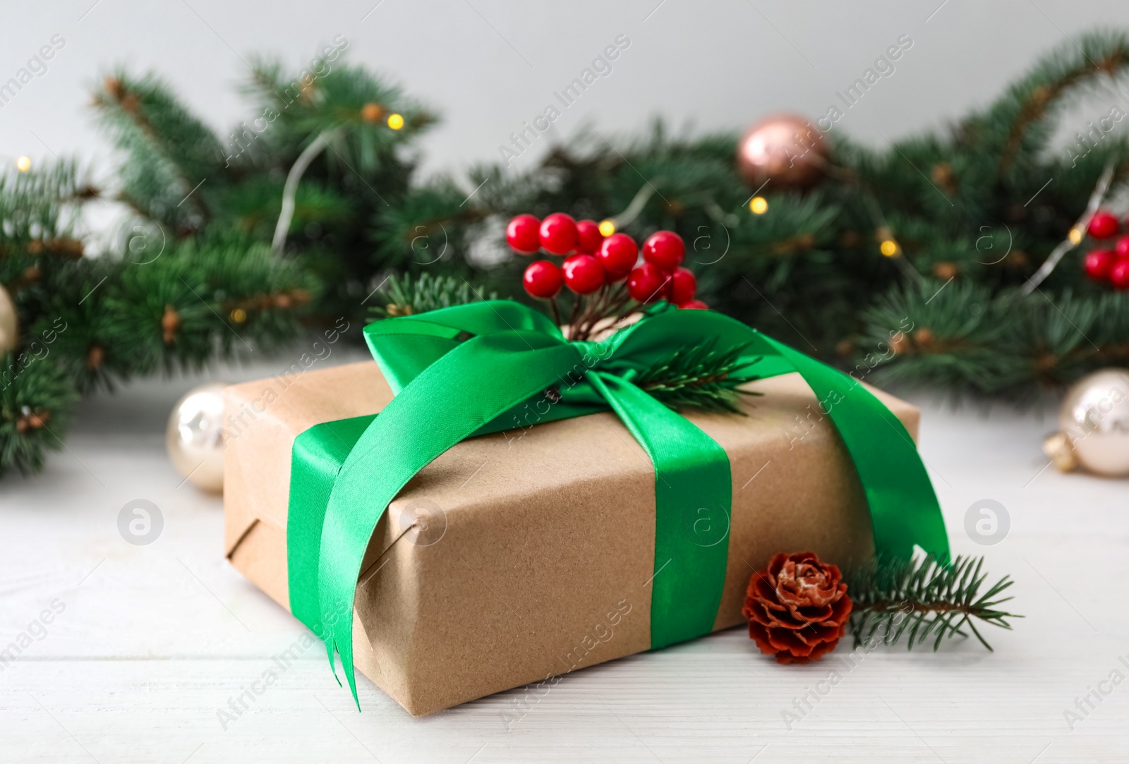 Photo of Christmas gift box with green bow and festive decor on white wooden table