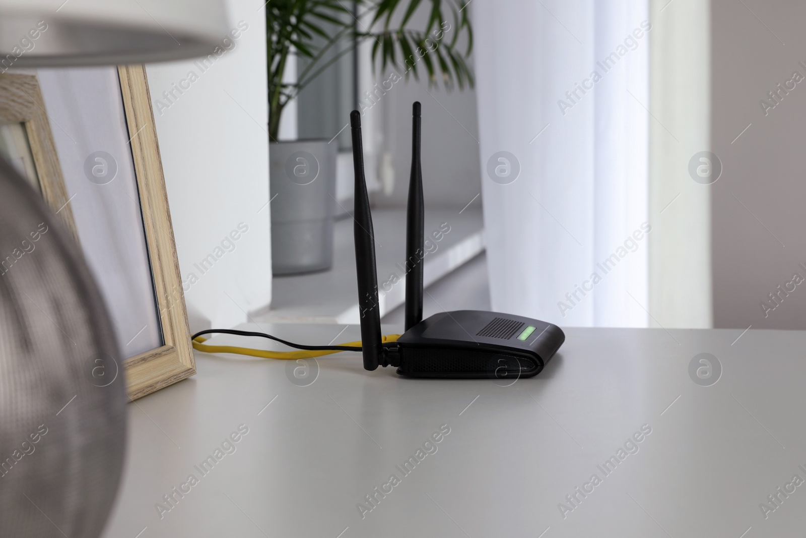 Photo of Modern Wi-Fi router on white table in room