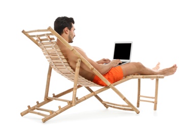 Young man with laptop on sun lounger against white background. Beach accessories