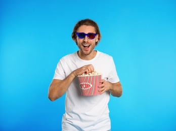 Photo of Man with 3D glasses and popcorn during cinema show on color background