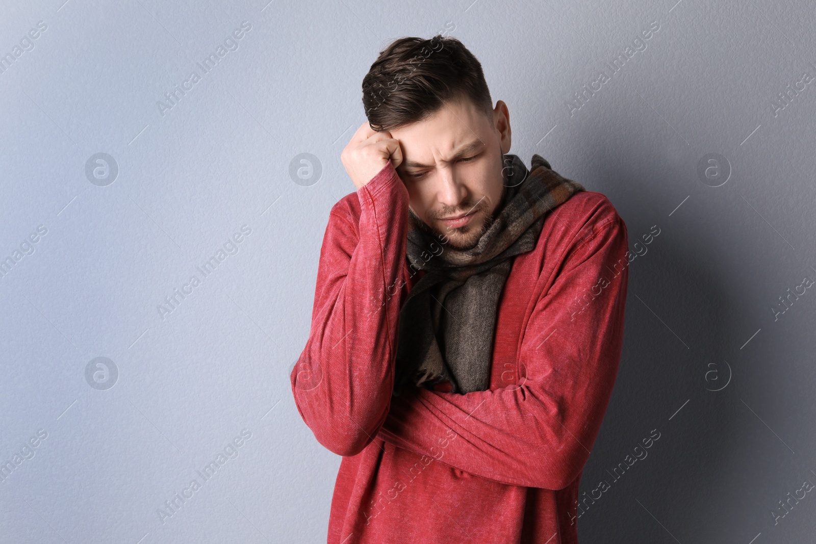 Photo of Mature man in warm clothes suffering from cold on color background