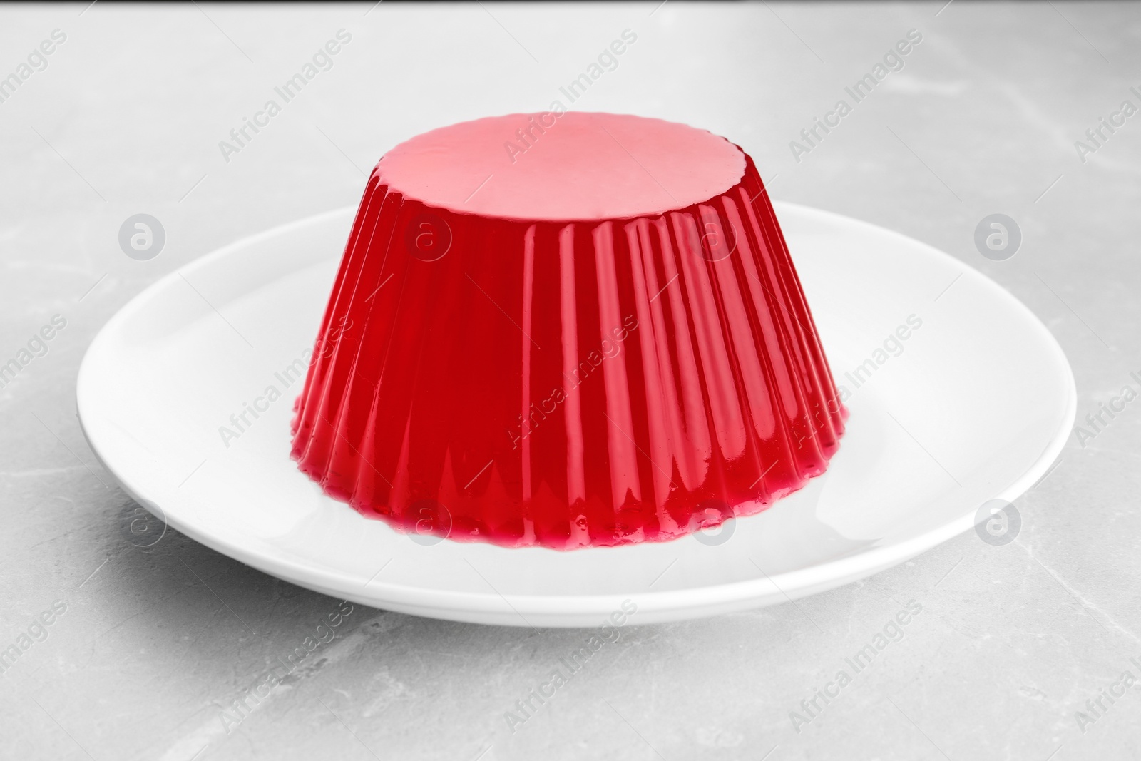 Photo of Plate with tasty fruit jelly on grey stone table