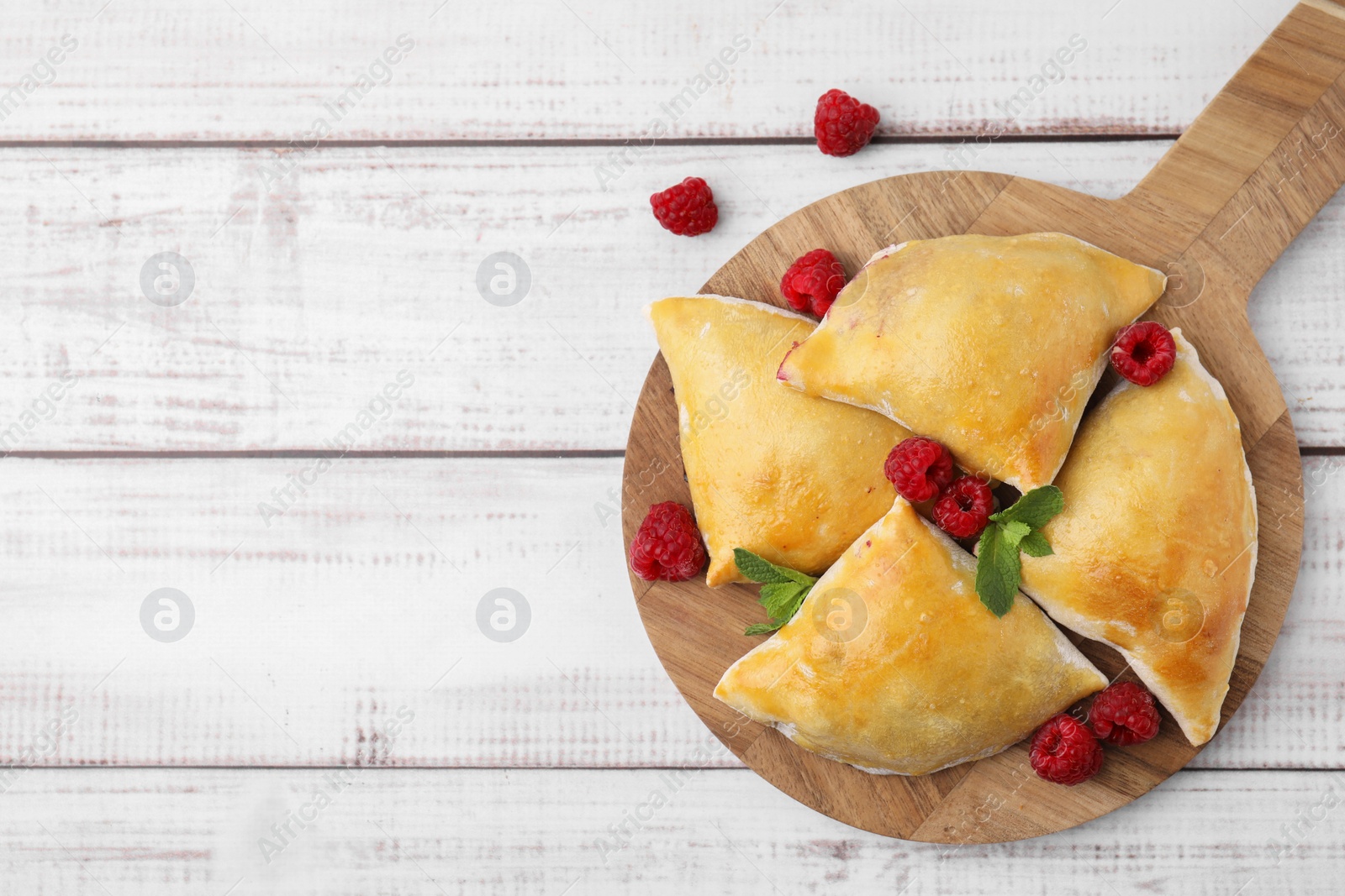 Photo of Delicious samosas with raspberries on white wooden table, flat lay. Space for text
