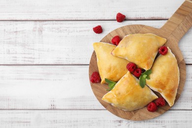 Delicious samosas with raspberries on white wooden table, flat lay. Space for text