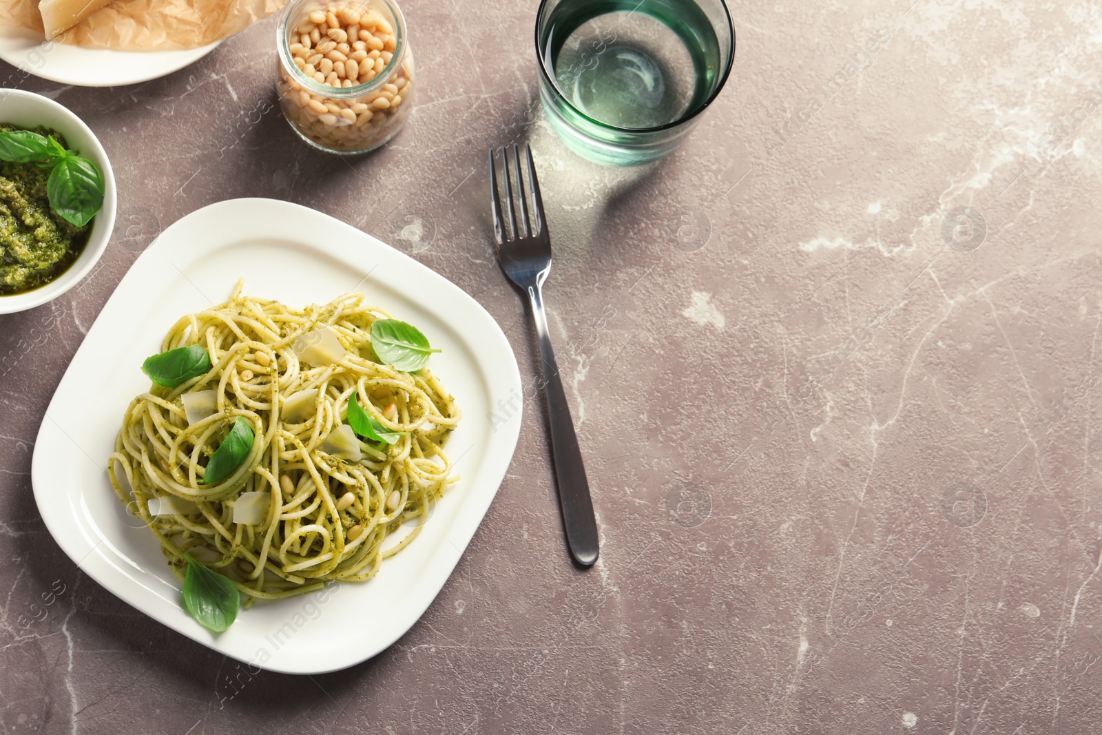 Photo of Flat lay composition with plate of delicious basil pesto pasta and space for text on gray table