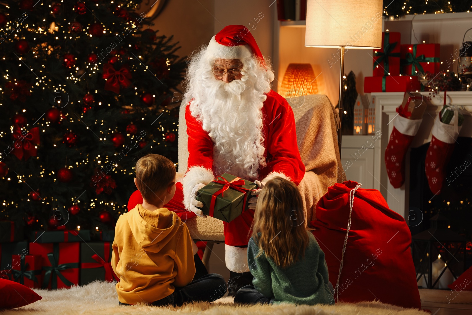 Photo of Merry Christmas. Santa Claus giving present to children at home