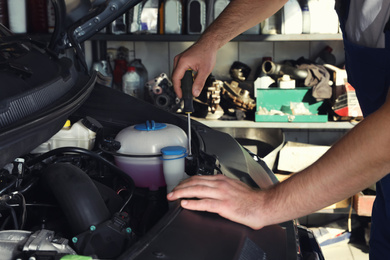 Professional auto mechanic fixing modern car in service center, closeup