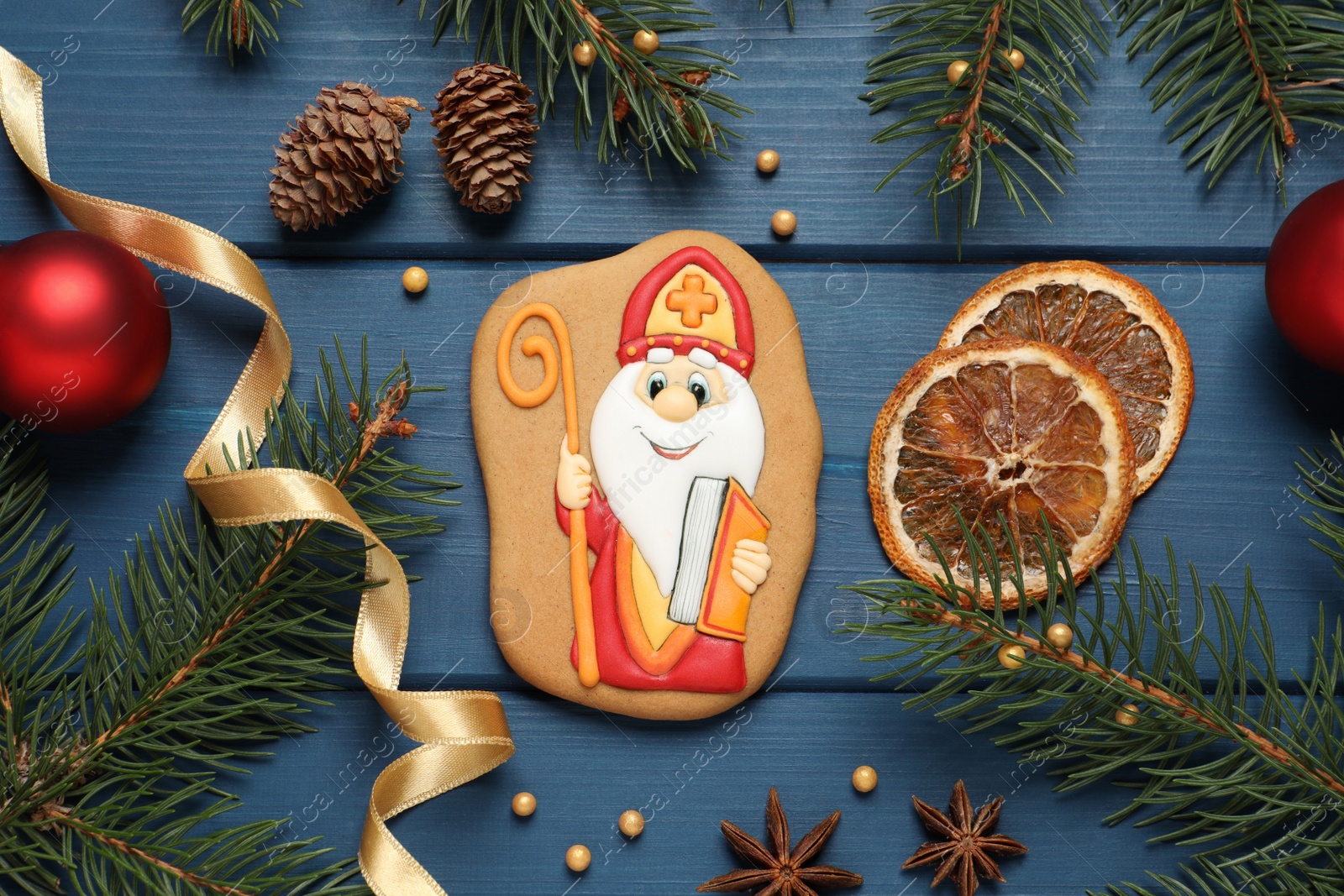 Photo of Tasty gingerbread cookie and festive decor on blue wooden table, flat lay. St. Nicholas Day celebration