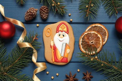 Tasty gingerbread cookie and festive decor on blue wooden table, flat lay. St. Nicholas Day celebration