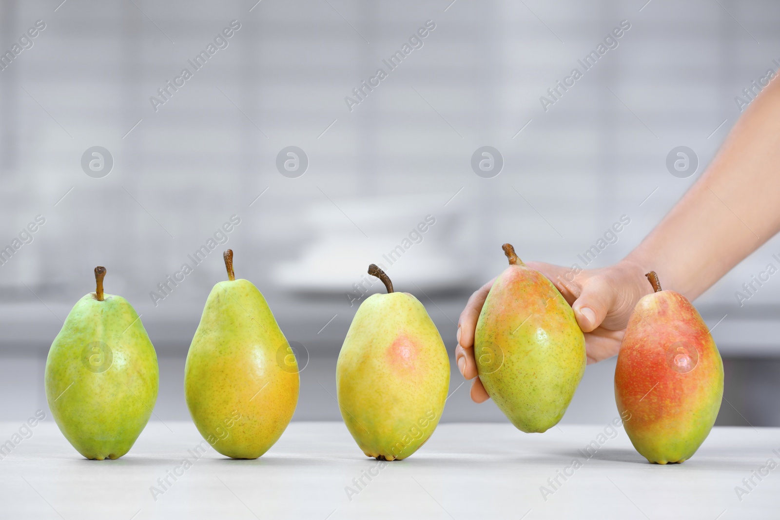 Photo of Woman taking fresh ripe pear from table in kitchen, closeup