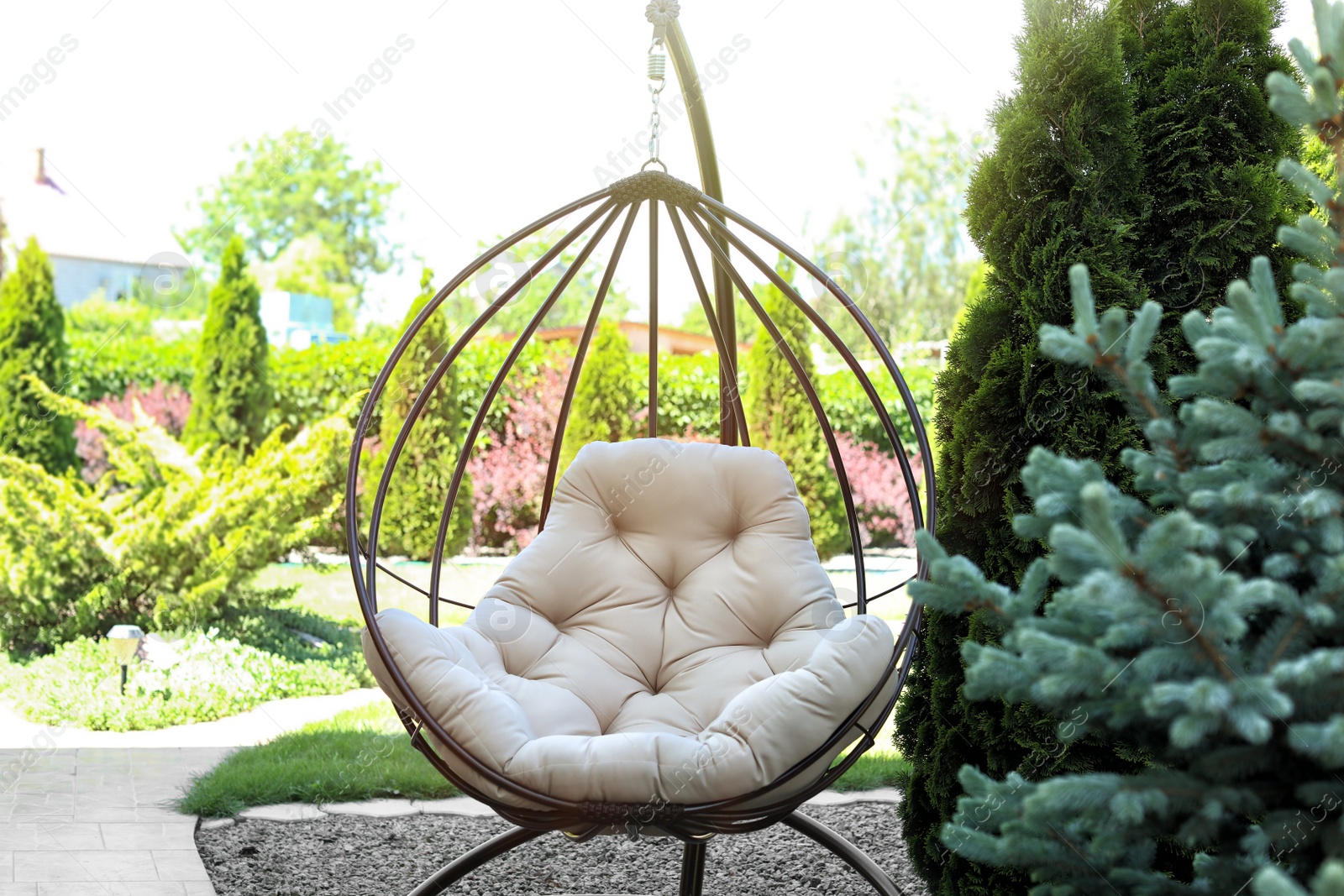 Photo of Beautiful English style garden with comfortable hanging chair on sunny day