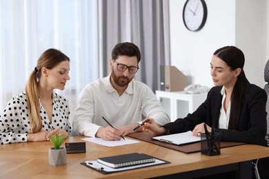 Photo of Couple signing document while having meeting with lawyer in office