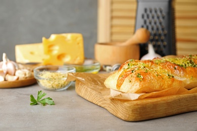 Photo of Tasty homemade garlic bread with cheese and herbs on grey table. Space for text