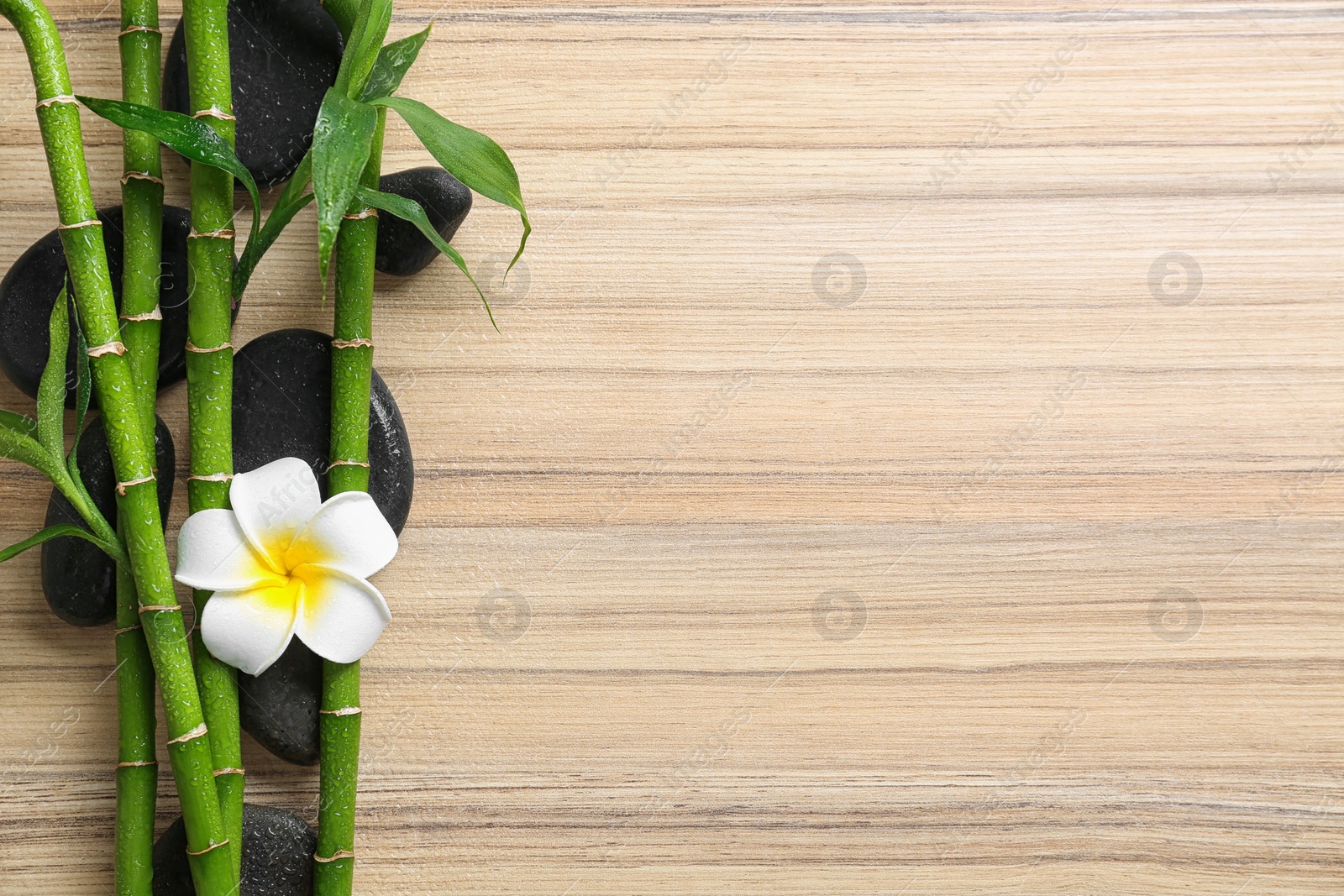 Photo of Flat lay composition with green bamboo stems on wooden background. Space for text