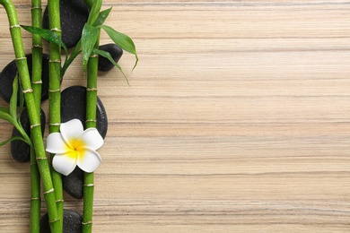 Flat lay composition with green bamboo stems on wooden background. Space for text