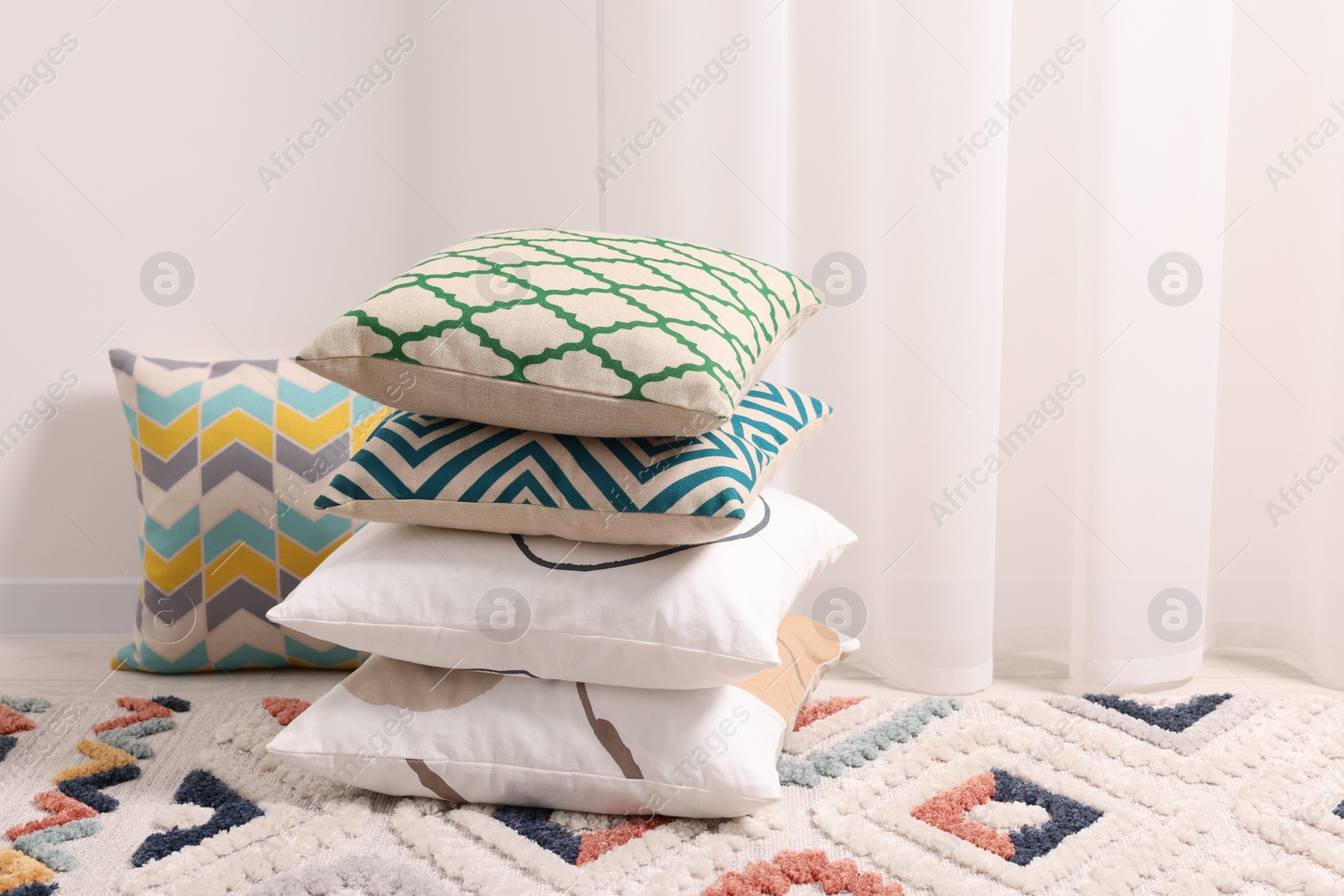 Photo of Stacked soft pillows on floor in room, space for text
