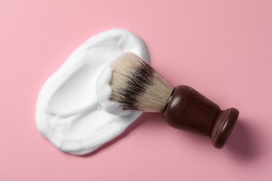 Photo of Brush with shaving foam on pink background, top view